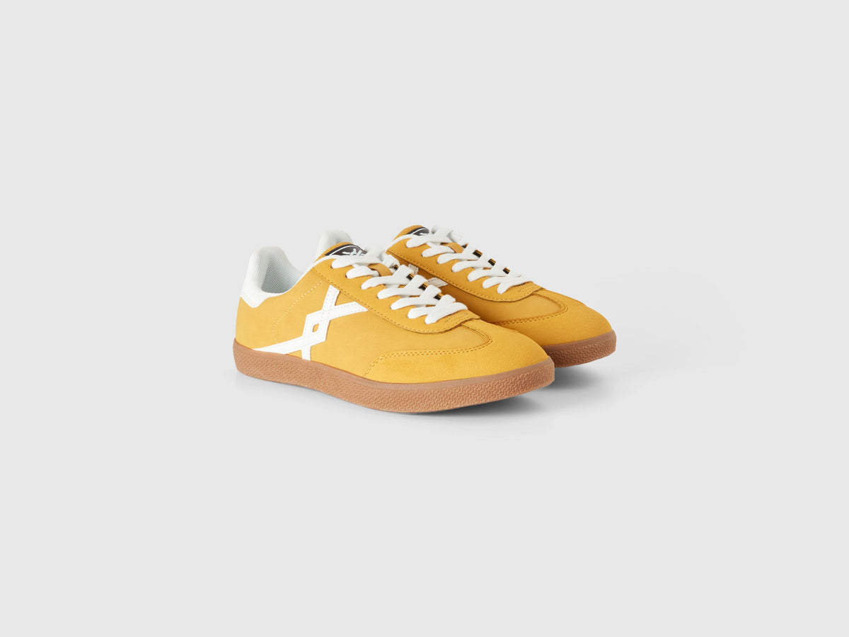 Pair of mustard yellow low-top sneakers with white accents.