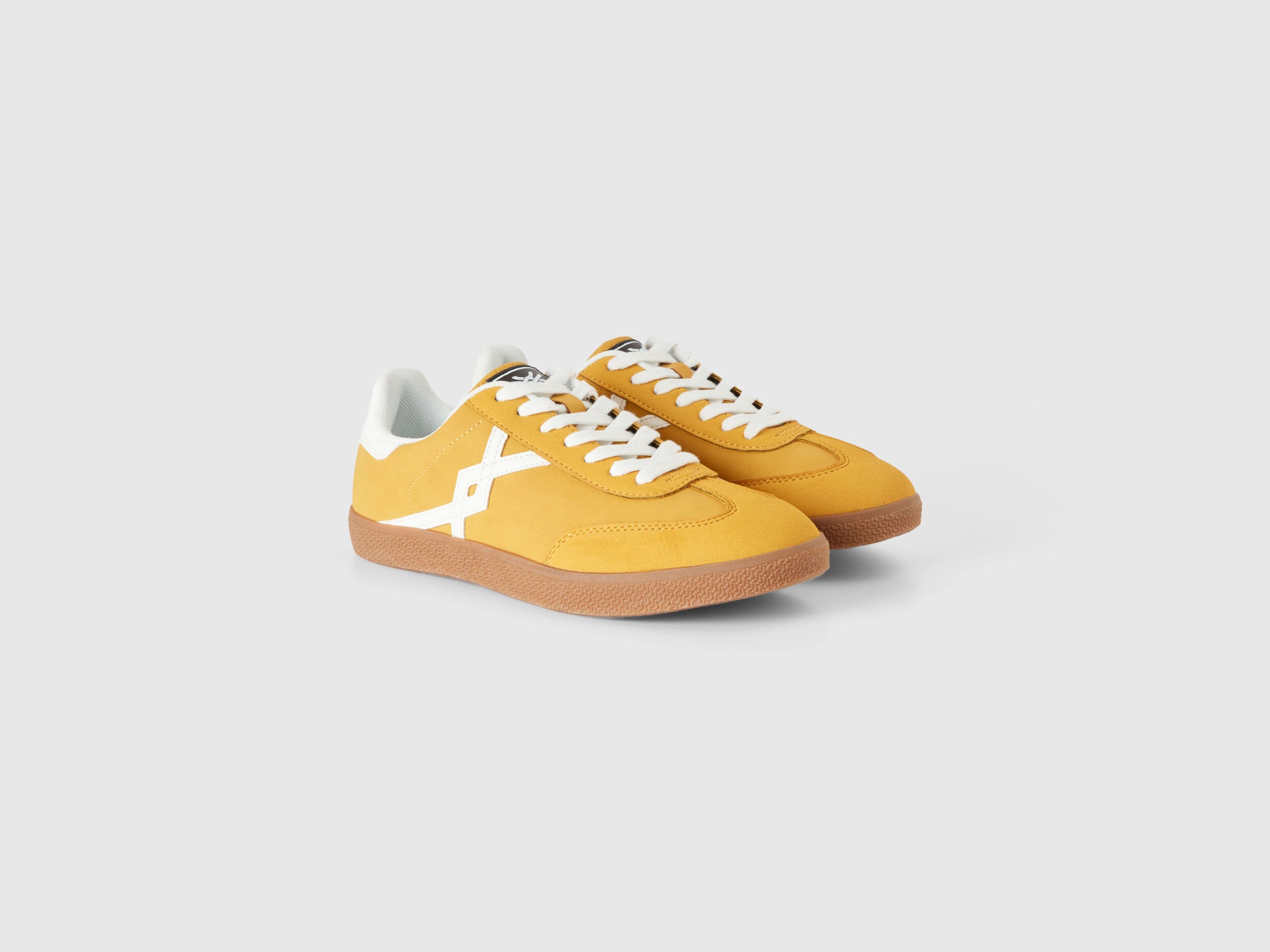 Pair of mustard yellow low-top sneakers with white accents.