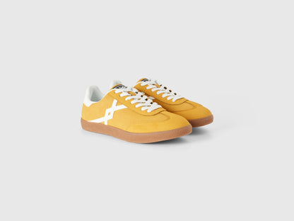 Pair of mustard yellow low-top sneakers with white accents.