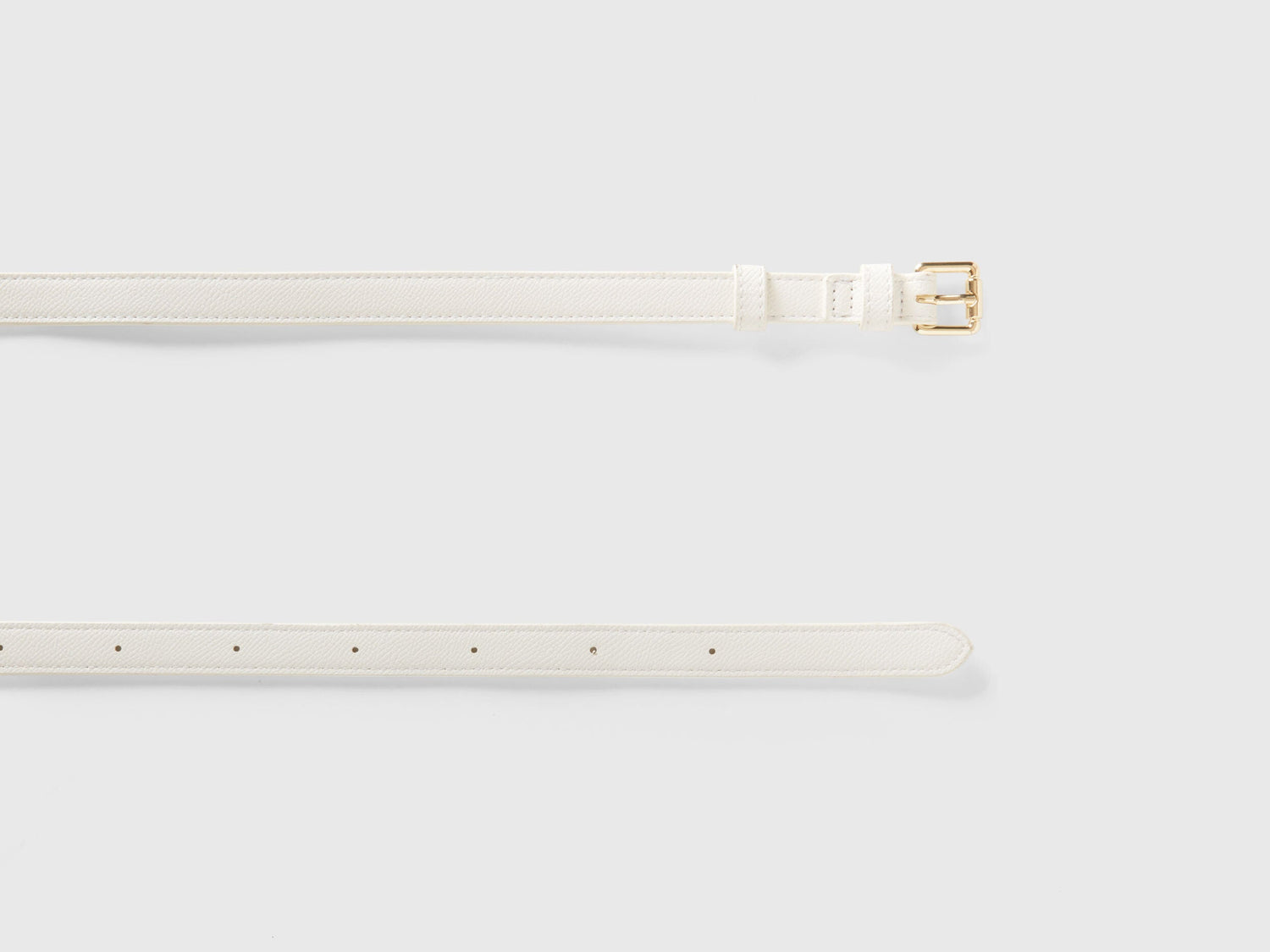 Unrolled white crocodile print corset belt, showcasing texture and gold buckle detail.