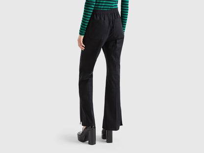 Back view of a woman wearing black flared pants and a striped green top.